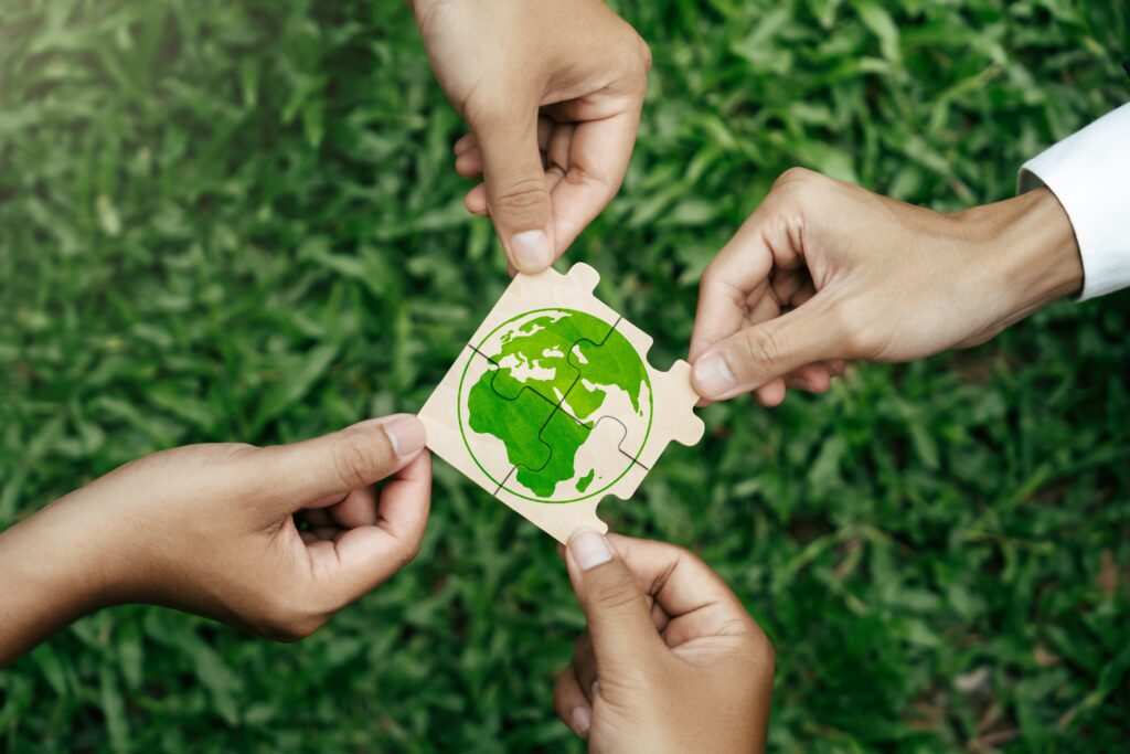 Four hands completing a puzzle of the world